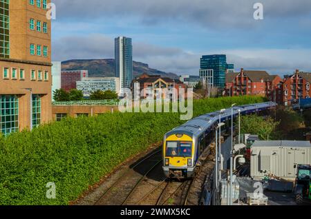 Belfast County Antrim Northern Ireland February 23 2024 - Train entering the station at Lanyon Place with city skyline behind Stock Photo