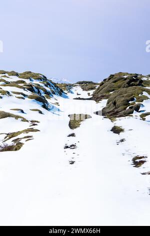 The snow-covered rocks and ground under a clear blue sky Stock Photo