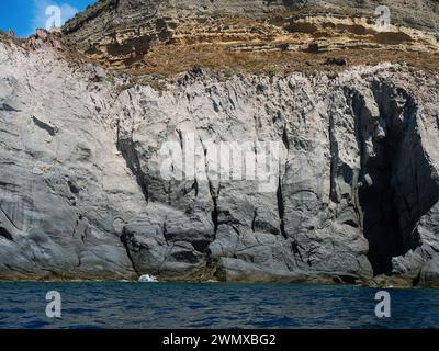 Weathered seaside rock face texture. Aged volcanic stone wall surface background pattern with cracks and scratches. Ischia Island, Italy. Stock Photo