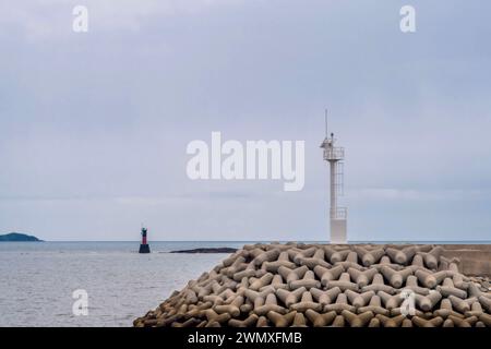 White light house on pier and red lighthouse on rocky point of small seaport in South Korea Stock Photo