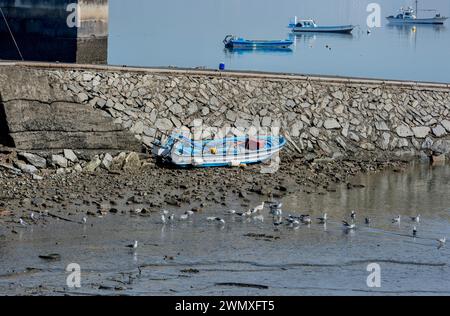 Small fishing boat with big container ship behind it Stock Photo