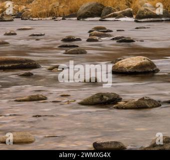 Smooth flowing river with rocks and dry grass in the diminishing light, in South Korea Stock Photo