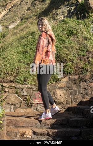 young blonde woman turning towards the camera on the landing of a staircase in the countryside Stock Photo