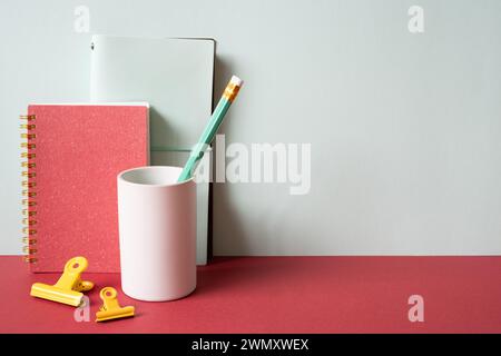 Diary notebook, pencil holder, clip on red desk. gray wall background. workspace Stock Photo