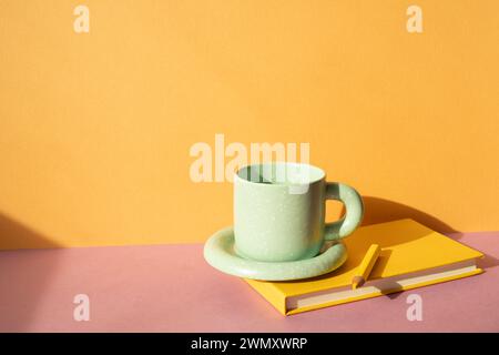 Notebook and colored pencil, coffee cup on pink desk. orange wall background. workspace Stock Photo