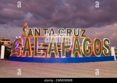 Santa Cruz Galapagos -Text Sign at the Puerto Ayora harbor during sunset withled lights on the galapagos island, Ecuador Stock Photo