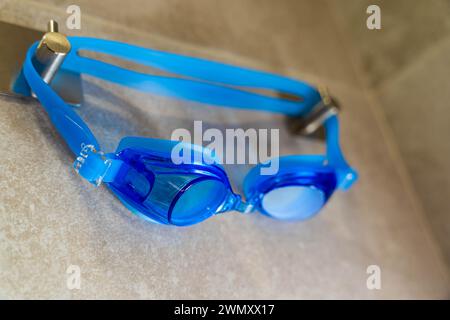 A pair of vibrant and stylish swimming goggles hanging on a hook in the shower room, ready for use. The bright colors and clean lines make them an app Stock Photo