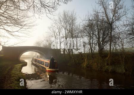 Narrow boat passing under Newton Bridge (no. 164) over the Leeds-Liverpool canal near Bank Newton, Gargrave, North Yorkshire. Stock Photo