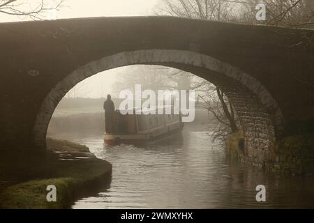 Narrow boat passing under Newton Bridge (no. 164) over the Leeds-Liverpool canal near Bank Newton, Gargrave, North Yorkshire. Stock Photo