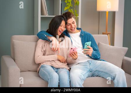 Happy multiethnic man and woman have fun browsing the internet smartphone.  Stock Photo
