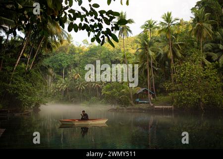 A man riding a boat at Paisu Pok Lake in Luk Panenteng, Banggai, Sulawesi, Indonesia. Stock Photo