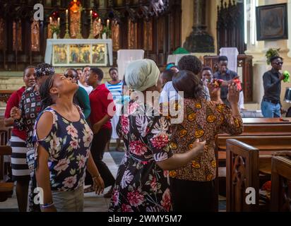 Women worshippers sing, dance and pray on a Sunday inside the Anglican Christ Church Cathedral in Stone Town, Zanzibar, Tanzania Stock Photo