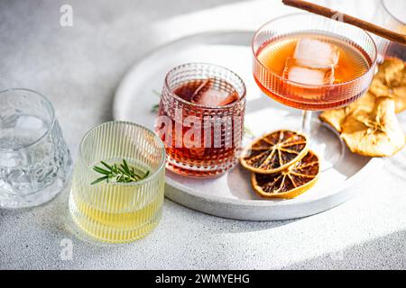 A diverse collection of spirits in ribbed glasses, including cherry liqueur with ice, limoncello with a rosemary sprig, and others, all resting tray w Stock Photo