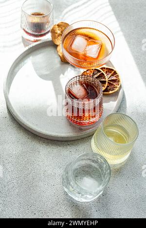Top view of shot of a variety of alcoholic drinks in textured glasses on a round concrete tray, with shadows cast by the bright daylight Stock Photo