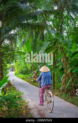 Vietnam, Mekong Delta, surroundings of Tra Vinh, woman traveling by bike in the countryside Stock Photo