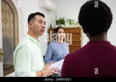 Three diverse colleagues in a professional setting reviewing a document together, focusing on teamwork and collaboration. Stock Photo