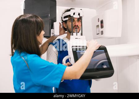 Dental professional assists a male patient with a 3D x-ray scan in a clinic. Stock Photo