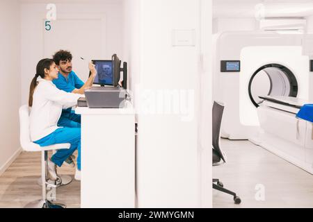 Two healthcare workers operate a magnetic resonance imaging (MRI) system in a modern medical clinic. Stock Photo