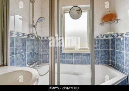 A well-lit bathroom featuring white fixtures and blue tiles. Stock Photo