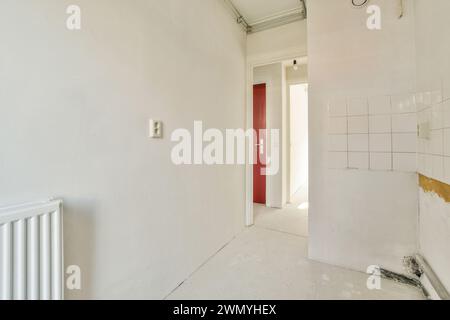 An empty, stark hallway with signs of wear and a red door at the end, requiring renovation. Stock Photo