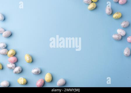 Festive Easter background. Multicoloured Easter eggs on a blue table. Card with a place for text. Top view. Stock Photo