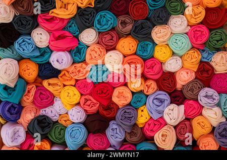 Rolls of colourful fabric stacked up closely together. Stock Photo