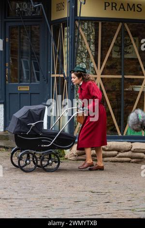 Grassington, Yorkshire, UK. 28th February 2024. Location filming begins for series 5 of the popular Channel 5 and PBS show All Creatures Great & Small. Cast and crew were spotted on the streets of the small Yorkshire Dales town of Grassington, which is converted, twice a  year, in to the fictional town of Darrowby. Pictured - Rachel Shenton (Helen Herriot) films a scene. Credit: Tom Holmes Photography / Alamy Live News). Stock Photo