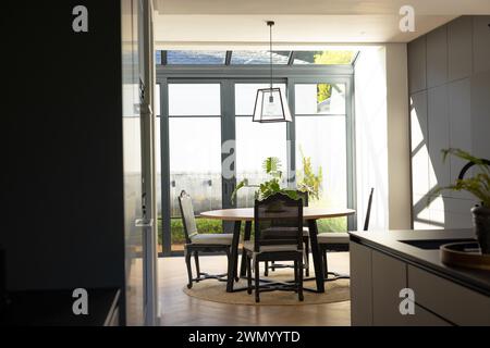 A modern dining area is bathed in natural light, featuring a round table and black chairs Stock Photo