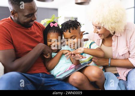 African American family enjoys time together, with the father showing something on a tablet Stock Photo