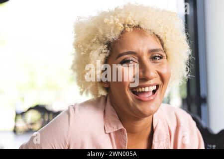 Young biracial woman with curly blonde hair laughs joyfully Stock Photo