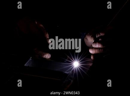 A man using a machine in his workshop in darkness Stock Photo