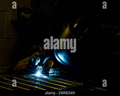 A man using a machine in his workshop in darkness Stock Photo