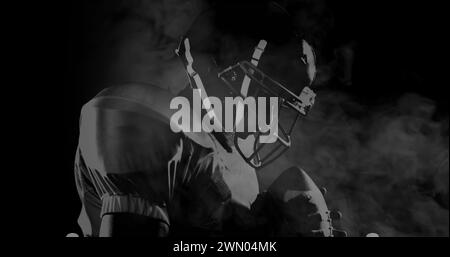 Image of male american football player over smoke on black background Stock Photo