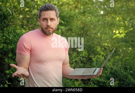 puzzled freelancer man work online. photo of freelancer man freelancing. freelancer man with laptop. freelancer man outdoor. Stock Photo