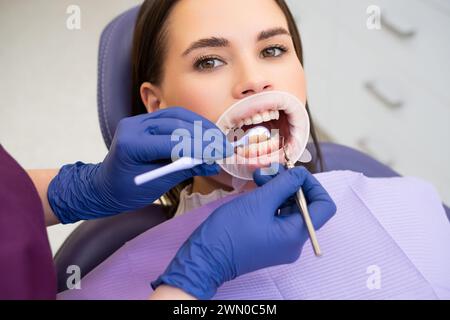 Portrait of young woman in dental clinic. Dentist in rubber gloves doing check up.  Stock Photo