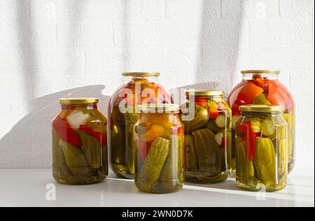 Glass jars with canned tomatoes and cucumbers on a white background. Close-up. Copy space. Stock Photo