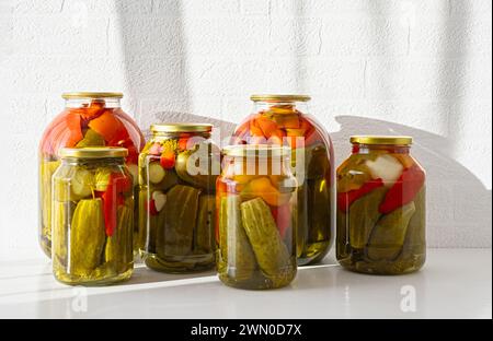 Pickled cucumbers and tomatoes in glass jars. Isolated on a white background. Close up. Copy space. Stock Photo