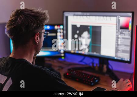 Young graphic designer working with two screens in his bedroom Stock Photo