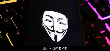Viersen, Germany - January 9. 2024: Smartphone screen with Anonymous mask symbol on computer keyboard as cyber attack and hacking concept Stock Photo