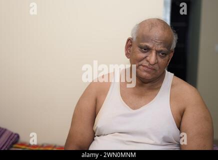 A peaceful elderly man sits on his bed Stock Photo