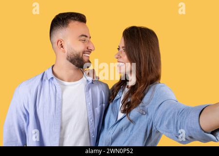 Joyful young couple taking selfie, looking at each other and smiling Stock Photo