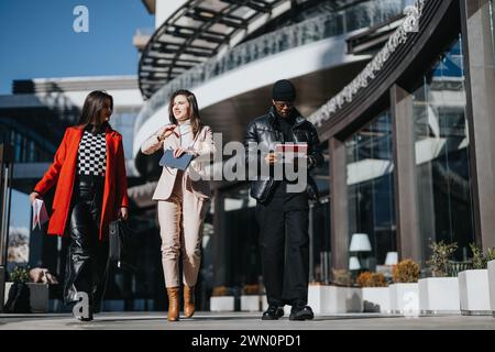 Multiethnic business professionals walking outdoors, engaged in work discussion. Stock Photo