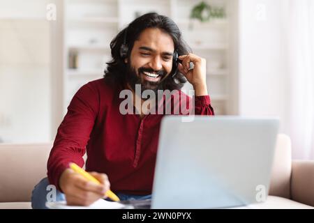Indian man studying from home, watching online lesson Stock Photo