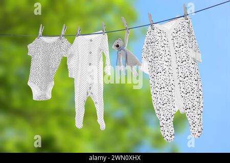 Baby clothes and crochet toy drying on washing line outdoors Stock Photo