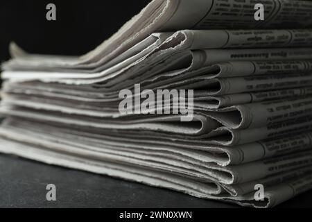 Stack of newspapers on dark stone table, closeup. Journalist's work Stock Photo