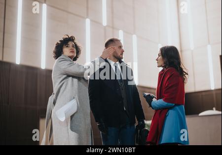 Stylish professionals in conversation at modern office lobby. Stock Photo