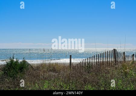 Specular highlights off ocean waves at Myrtle Beach viewed behind sand dunes Stock Photo