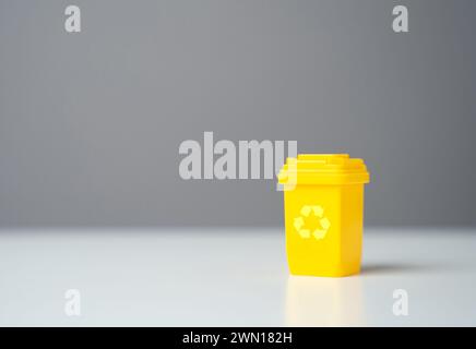 Yellow recycling bin and copy space. Circular economy. Conserve natural resources, reduce waste, create jobs in recycling industry. Selling recycled m Stock Photo