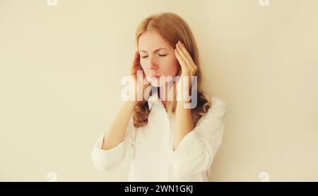 Exhausted tired caucasian young woman employee with headache or temples pain, suffers from migraine, tension in the head at home or office Stock Photo