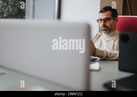 Focused professional man working at a computer desk in modern office Stock Photo